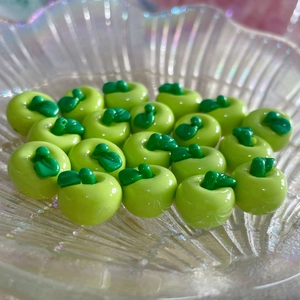 Vista macro di ciondoli a forma di mela verde in resina per gioielli e accessori per capelli
