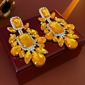 Detailed view of yellow crystal earrings with silver-tone metal and rhinestone inlay