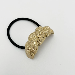 Macro detail of elastic hair tie with a luxury sand gold peanut-shaped alloy ornament
