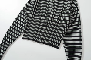 Detailed view of the striped knit sweater featuring black and green patterns and button closure