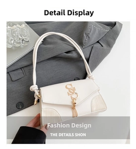 Close-up of white leather square bag with golden logo tassel and knot strap details