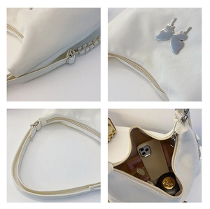 Macro detail of white PU leather bag with metal butterfly and chain strap features