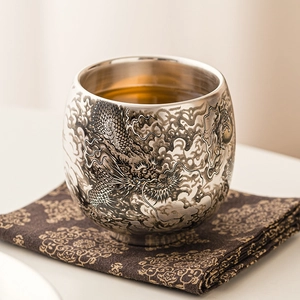 Tasse à thé en argent 999 avec relief de dragon sur un tapis traditionnel