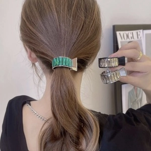Detail of floral chiffon hair clips in green and black colors on model and in hand