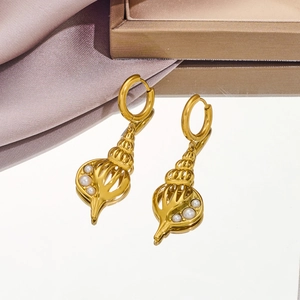 Detailed macro view of gold shell earrings with small pearls on elegant purple silk