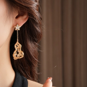 Gros plan d'un mannequin portant des boucles d'oreilles fleur gourde dorées en zircon