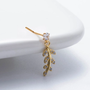 Gold stainless steel nose stud with zircon leaf pendant on a white ceramic display