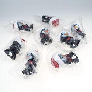 Detail of wind-up penguin toys in individual plastic packaging on light grey background