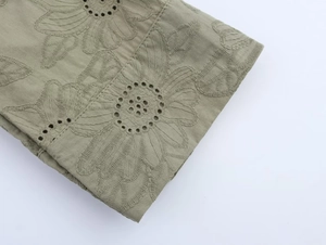 Detail of olive green embroidery and eyelet design on cotton linen fabric