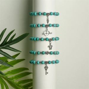 Detail of bohemian turquoise beaded bracelets with silver wing and heart charms