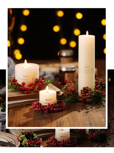 Three white pillar candles with red berry and pine cone wreath on a rustic wooden table