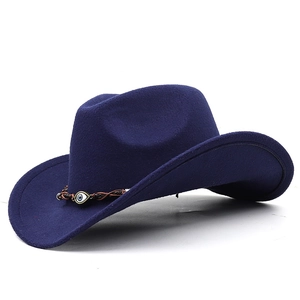 Detail of dark blue western cowboy hat featuring braided brown band and evil eye pendant