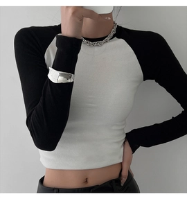 Close-up of contrast rib-knit crop top with long raglan sleeves and silver jewelry detail