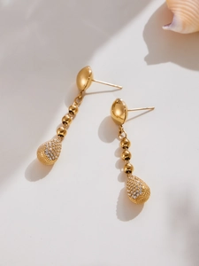 Détail de boucles d'oreilles dorées avec perles de riz et zircons clairs