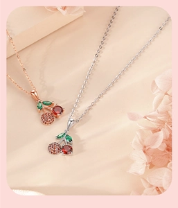 Macro detail of cherry pendant necklace with red crystals in silver and rose gold finish