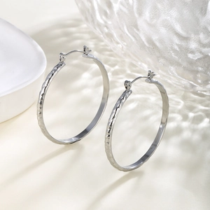 Close-up of silver chain textured hoop earrings with a handcrafted hammered finish surface