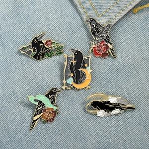 Gothic raven and rose enamel pin set with crescent moon motifs on blue denim fabric