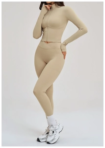 Detail of high-waisted yoga pants with cross waistband and side pockets in beige color