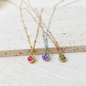 Detail of round colorful birthstone pendants in gold, silver, and rose gold settings