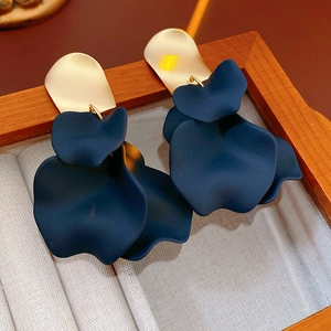 Close-up of irregular dark blue flower petal earrings with gold metal studs in a gift box