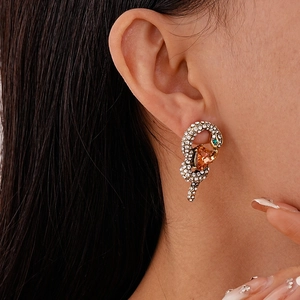 Detailed shot of a snake-shaped earring with amber heart stone and silver diamonds