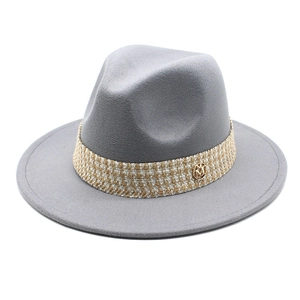 Detail of grey wool fedora hat featuring woven plaid band and metallic M logo accent