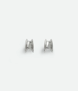 Macro shot of silver geometric hoop earrings with a high-polish mirror finish