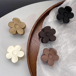Detailed top view of five matte floral shark hair clips in assorted neutral colors