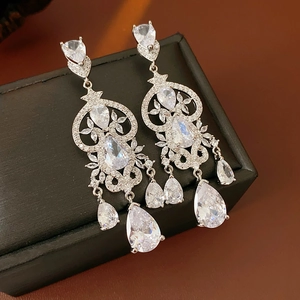 Detail of silver drop earrings with zircons and tassels on a black jewelry box