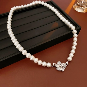 Detail of white pearl necklace with a silver floral clasp and sparkling cubic zirconia