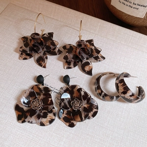 Flat lay of leopard print resin flower earrings and C-shaped hoops on a beige texture