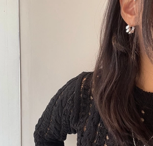 Close-up of a twisted silver hoop earring worn on ear with minimalist style aesthetics