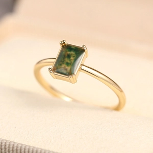 Macro detail of gold ring with rectangle moss agate stone in a four-prong setting