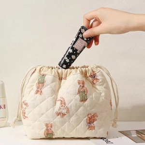 Close-up of quilted beige bear pattern drawstring pouch with hand cream in a set