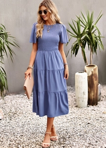 Detailed view of blue tiered dress with pleated bodice and short sleeves on a model