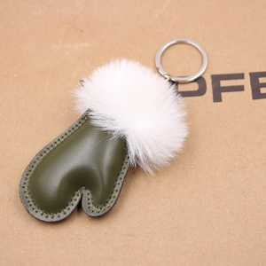Detail of army green leather glove keychain with fluffy white faux fur ball and metal ring
