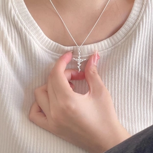 Close-up of a 925 sterling silver rose cross pendant necklace on a female model
