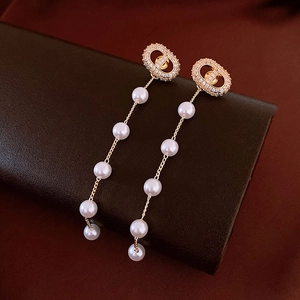 Detail view of long tassel earrings with gold-tone pig nose motif and gradient pearls