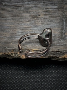 Macro shot of vintage bronze adjustable ring with iridescent raw stone on wooden surface