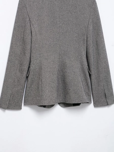 Detailed close-up of grey herringbone fabric texture and cuff on women's suit jacket