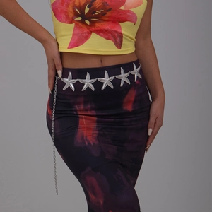 Close-up of silver starfish chain belt with layered pendants on printed summer dress