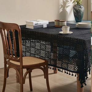 Close-up of black lace tablecloth with fringe edge on a rustic wooden dining table