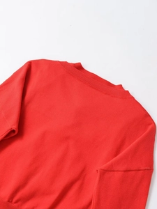 Detail shot of a vibrant red knitted jacket featuring a classic ribbed crew neck design