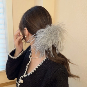 Vue détaillée de la grande pince à cheveux en plumes grises portée par un mannequin élégant