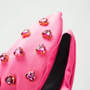 Haarreif aus rosa Stoff mit herzförmigen rosa Kristallen und Goldfassung