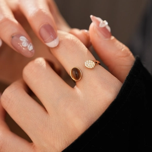 Détail d'une bague dorée ajustable avec pierre œil de tigre brune et zircons brillants