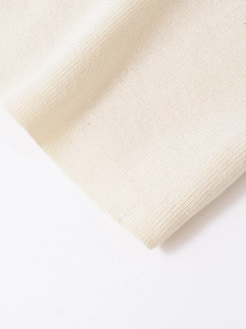 Close-up of cream knit fabric showing high-quality texture and split back detail