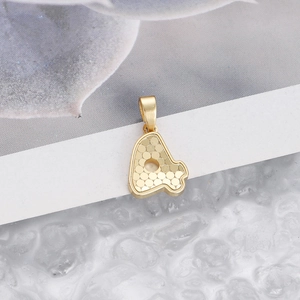 Macro shot of a gold honeycomb texture circular pendant on a minimalist white card