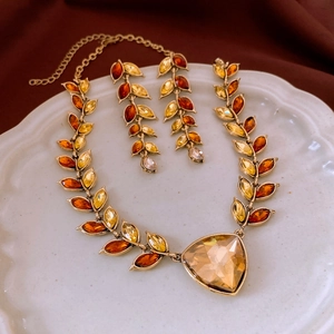 Exquisite gold-plated wheat ear jewelry set with amber crystals on a vintage ceramic tray