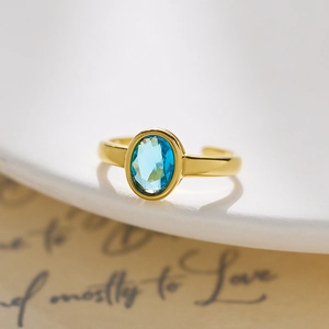 Detail of gold oval blue gemstone ring with adjustable band on vintage background